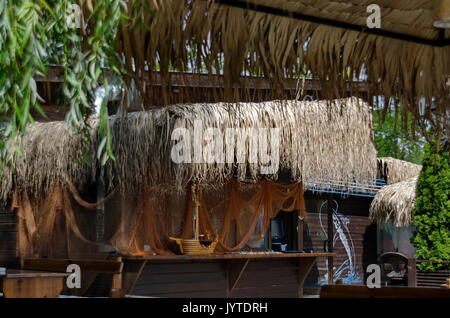 Blick auf die gemütliche Frühstücksecke für Sommer Erholung unter Palm Sonnenschirm mit Bar, Tisch, Stuhl und Bank aus Holz, park Borisova Gradina, Sofia, Bulgarien Stockfoto