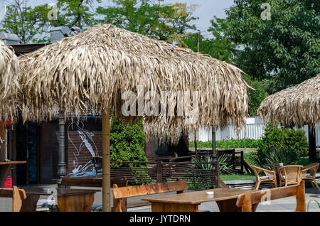 Blick auf die gemütliche Frühstücksecke für Sommer Erholung unter Palm Sonnenschirm mit Tisch, Stuhl und Bank aus Holz, park Borisova Gradina, Sofia, Bulgarien Stockfoto