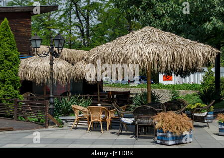 Blick auf die gemütliche Frühstücksecke für Sommer Erholung unter Palm Sonnenschirm mit Tisch, Stuhl und Bank aus Holz, park Borisova Gradina, Sofia, Bulgarien Stockfoto