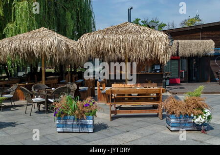 Blick auf die gemütliche Frühstücksecke für Sommer Erholung unter Palm Sonnenschirm mit Bar, Tisch, Stuhl und Bank aus Holz, park Borisova Gradina, Sofia, Bulgarien Stockfoto