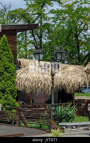 Blick auf die gemütliche Frühstücksecke für Sommer Erholung unter Palm Sonnenschirm mit Tisch, Stuhl und Bank aus Holz, park Borisova Gradina, Sofia, Bulgarien Stockfoto