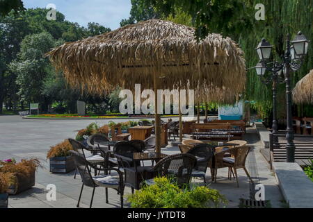 Blick auf die gemütliche Frühstücksecke für Sommer Erholung unter Palm Sonnenschirm mit Tisch, Stuhl und Bank aus Holz, park Borisova Gradina, Sofia, Bulgarien Stockfoto