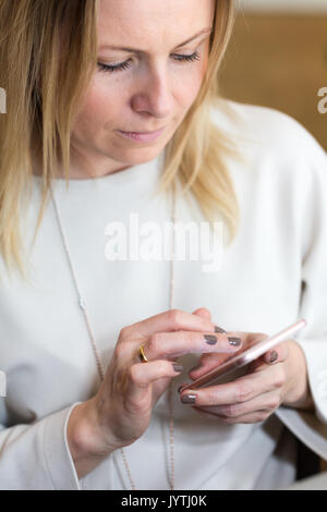 Junge blonde Haare Business woman schriftlich eine SMS-Nachricht mit Messenger auf Handy. Candid unposed Portrait. Vertikale Ausrichtung Stockfoto