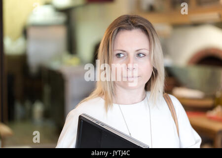 Junge Erwachsene Business woman holdig einen Laptop und weg schauen mit einem Lächeln auf dem Gesicht. Horizontale ehrliches Porträt Stockfoto