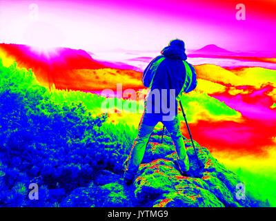 Uv-Scan. Infrarot Foto. Happy Fotoenthusiast genießen Sie Fotografie der Fall Tagesanbruch in der Natur auf einer Klippe auf Fels. Verträumt foggy landscap Stockfoto