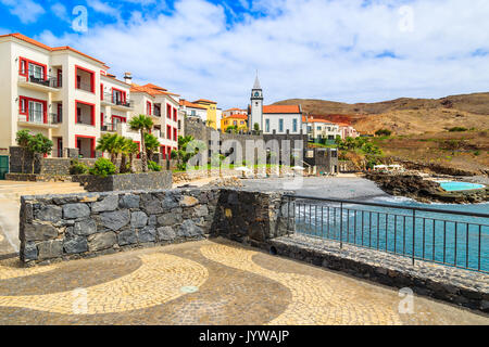 Blick auf die farbenfrohen Häuser und Gebäude der Kirche auf der Uferpromenade in der Nähe von Canical Stadt, Insel Madeira, Portugal Stockfoto