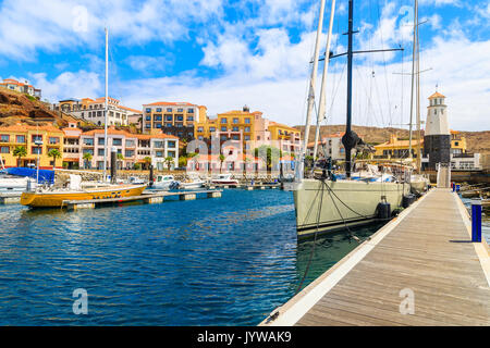 Segelboote im Hafen mit bunten Häusern in der Nähe von Canical Stadt an der Küste der Insel Madeira, Portugal Stockfoto