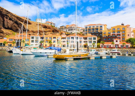 Segelboote im Jachthafen mit bunten Häusern in der Nähe von Canical Stadt an der Küste der Insel Madeira, Portugal Stockfoto