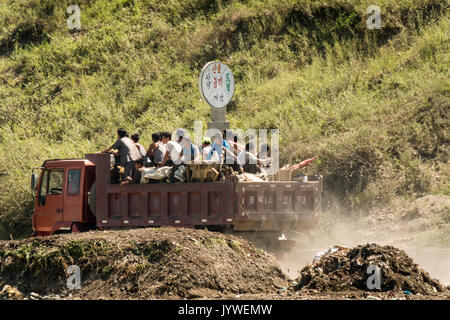 Hyesan, Ryanggang Provinz, Nordkorea - August 7, 2017: die Menschen stehen auf einem offenen Lastwagen fahren auf einer staubigen Straße. Stockfoto