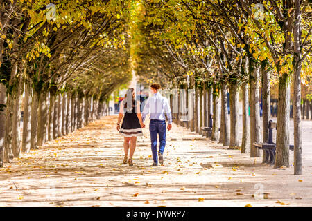 Paar gehen Hand in Hand zwischen den Reihen von Bäumen im Jardin du Palais Royal in Paris. Stockfoto