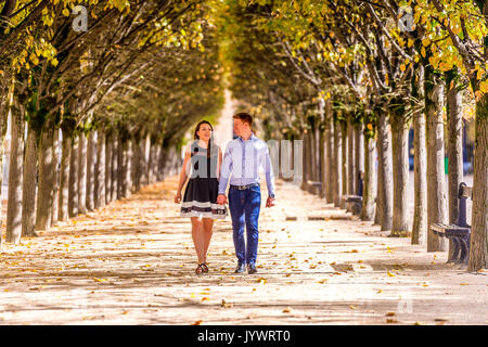 Paar gehen Hand in Hand zwischen den Reihen von Bäumen im Jardin du Palais Royal in Paris. Stockfoto