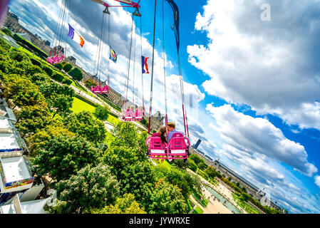 Auf den Schwingenden Sesseln fährt Paar durch die Luft über die Tuileries Gardens. Stockfoto