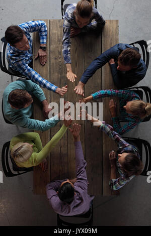 Moderne business meeting Konzept, Menschen in Freizeitkleidung sitzen um Holz- Tabelle, High Five Stockfoto