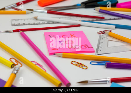 Weiß Schreibtisch mit Farbstiften verstreut und Nahaufnahme eines zurück zu Schule Hinweis auf einem rosa Pad Stockfoto