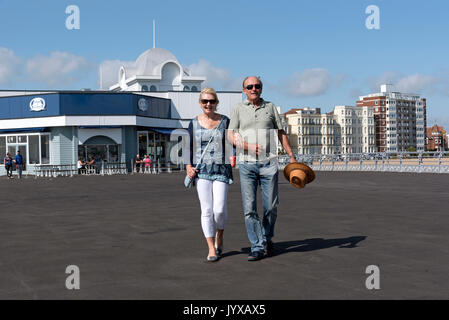 Ältere paar Urlauber gehen Arm in Arm auf einem Pier am Meer im Süden von England Großbritannien Stockfoto