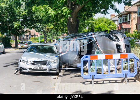 Ergebnis von Verkehrsunfall in suburban Wohnstraße. Silber Nissan Qashqai Visia Auto umgeworfen auf Seite auf Pflaster & mit Polizei Klebeband bedeckt. Stockfoto