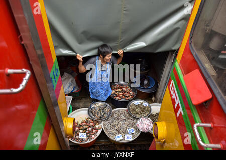 (170821) - MAEKLONG, Aug 21, 2017 (Xinhua) - ein Fisch Verkäufer steht von der Rail Track als Nahverkehrszug durch Maeklong Markt in der zentralen Provinz Samut Songkhram Thailand, Aug 18, 2017 läuft. In Maeklong Markt, entlang einer Bahnstrecke gebaut, ein Kompromiss zwischen Anbietern und vorbei an S-Bahnen erreicht. Wenn die Rail Track ist klar, stall Besitzer bis Ständen zu werden; noch acht Mal pro Tag, die Markisen und einige der Waren haben, die von der Schiene verschoben werden und machen Weg für ankommende und abfahrende Züge. Die business Stil um Fahrpläne hat Maeklong Marke gemacht Stockfoto