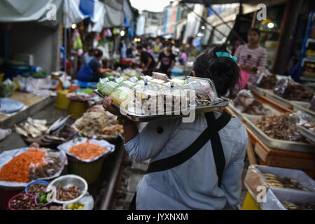 (170821) - MAEKLONG, Aug 21, 2017 (Xinhua) - ein Anbieter verkauft Snacks an Maeklong Markt in der zentralen Provinz Samut Songkhram Thailand, Aug 20, 2017. In Maeklong Markt, entlang einer Bahnstrecke gebaut, ein Kompromiss zwischen Anbietern und vorbei an S-Bahnen erreicht. Wenn die Rail Track ist klar, stall Besitzer bis Ständen zu werden; noch acht Mal pro Tag, die Markisen und einige der Waren haben, die von der Schiene verschoben werden und machen Weg für ankommende und abfahrende Züge. Die business Stil um Fahrpläne hat Maeklong Markt einer der einzigartigsten Märkte in Thailand. (Xinh Stockfoto