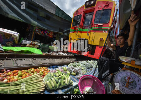 (170821) - MAEKLONG, Aug 21, 2017 (Xinhua) - ein Nahverkehrszug läuft durch Maeklong Markt in der zentralen Provinz Samut Songkhram Thailand, Aug 19., 2017. In Maeklong Markt, entlang einer Bahnstrecke gebaut, ein Kompromiss zwischen Anbietern und vorbei an S-Bahnen erreicht. Wenn die Rail Track ist klar, stall Besitzer bis Ständen zu werden; noch acht Mal pro Tag, die Markisen und einige der Waren haben, die von der Schiene verschoben werden und machen Weg für ankommende und abfahrende Züge. Die business Stil um Fahrpläne hat Maeklong Markt einer der einzigartigsten Märkte in Thailand. Stockfoto