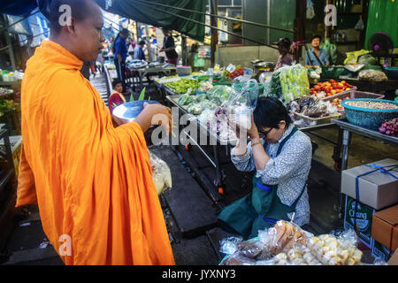 (170821) - MAEKLONG, Aug 21, 2017 (Xinhua) - ein Stall Besitzer (R) gibt Almosen zu einem buddhistischen Mönch Maeklong Markt in der zentralen Provinz Samut Songkhram Thailand, Aug 20, 2017. In Maeklong Markt, entlang einer Bahnstrecke gebaut, ein Kompromiss zwischen Anbietern und vorbei an S-Bahnen erreicht. Wenn die Rail Track ist klar, stall Besitzer bis Ständen zu werden; noch acht Mal pro Tag, die Markisen und einige der Waren haben, die von der Schiene verschoben werden und machen Weg für ankommende und abfahrende Züge. Die business Stil um Fahrpläne hat Maeklong Markt einer der einzigartigsten Stockfoto