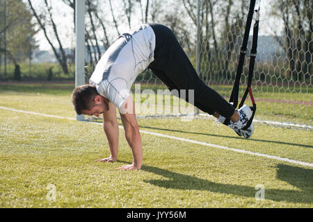 Junger Mann tun Crossfit mit Trx Fitness Bänder in Stadt Park - Ausbildung und Training für Ausdauer - Gesunder Lebensstil Konzept Outdoor Stockfoto