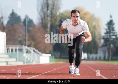 Attraktiver Mann Sprintete auf der Laufbahn im City Park Bereich - Ausbildung und Training für Ausdauer, Fitness gesunder Lebensstil Konzept Outdoor Stockfoto