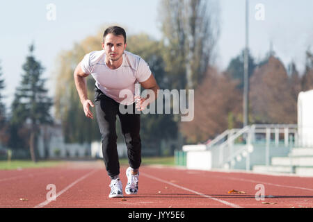 Attraktiver Mann Sprintete auf der Laufbahn im City Park Bereich - Ausbildung und Training für Ausdauer, Fitness gesunder Lebensstil Konzept Outdoor Stockfoto