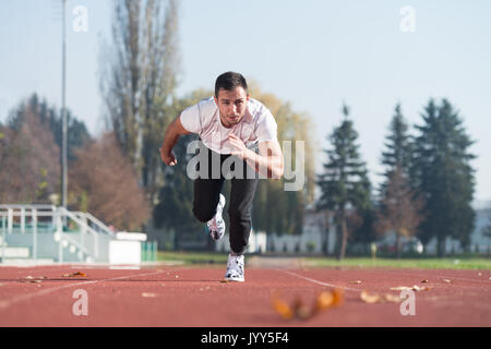 Attraktiver Mann Sprintete auf der Laufbahn im City Park Bereich - Ausbildung und Training für Ausdauer, Fitness gesunder Lebensstil Konzept Outdoor Stockfoto