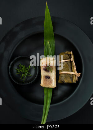 Thailändisches dessert Paar Banane in klebrigen Reis und schwarze Bohnen eingewickelt in Bananenblätter Stockfoto