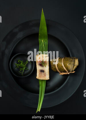 Thailändisches dessert Paar Banane in klebrigen Reis und schwarze Bohnen eingewickelt in Bananenblätter Stockfoto