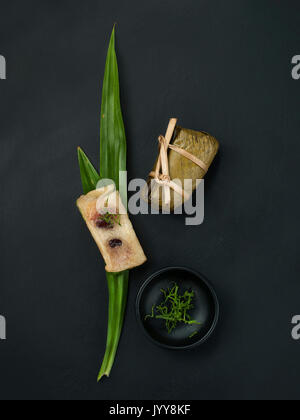 Thailändisches dessert Paar Banane in klebrigen Reis und schwarze Bohnen eingewickelt in Bananenblätter Stockfoto