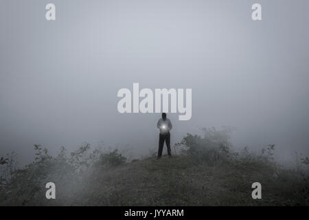 Bedrohlicher Mann in Hoodie im Nebel Shing Licht Stockfoto