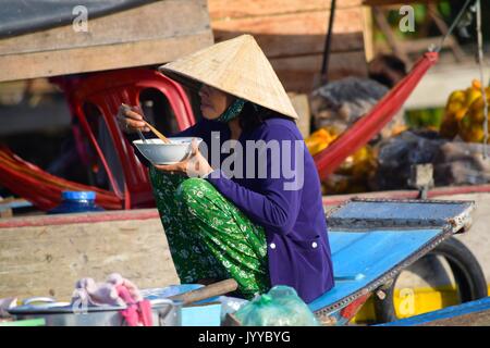 Eine Frau frühstückt auf den schwimmenden Märkten von Can Tho im Mekong-Delta, Vietnam. Stockfoto