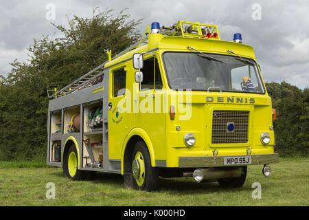 1970 Vintage Dennis Brand gerät in gelbe Lackierung in einer ländlichen Umgebung stationär. Seitenblenden geöffnet und zeigt die erhaltenen Löschausrüstung. Stockfoto