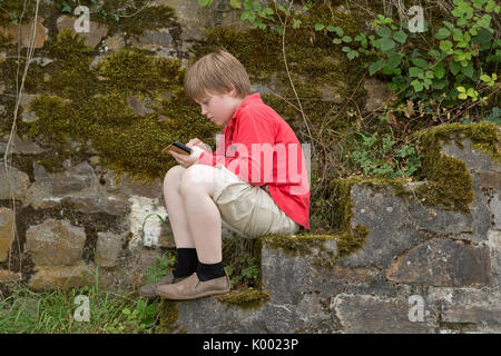 Junge Junge sitzt auf Treppe mit seinem Smartphone Stockfoto