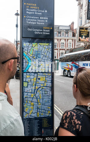 Zwei Menschen betrachten ein touristische Informationen Zeichen außerhalb des Gielgud Theatre Shaftesbury Avenue London, England Stockfoto