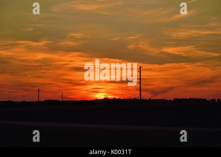 Burlington, Illinois, USA. Leuchten von der untergehenden Sonne sichtbar über ländliche Telefonleitungen. Stockfoto