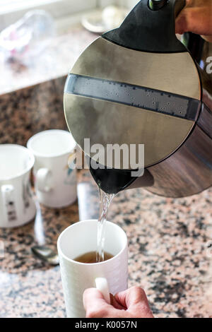 Gießen Sie eine Tasse Tee oder Kaffee aus einem Wasserkocher Stockfoto