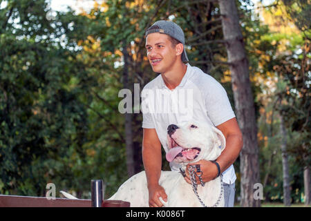 Teenager boy Spaziergänge mit seinem Hund im Park - Dogo Argentino Stockfoto