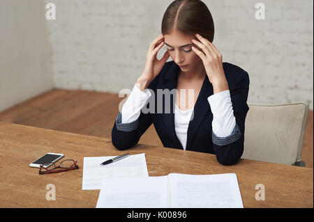 Überbelasten business Frau leidet unter Kopfschmerzen im Büro sitzen und Lesen von Dokumenten Stockfoto
