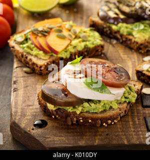 Vielzahl von Avocado Toast auf einem Schneidebrett Stockfoto