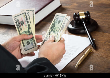 Hohe Betrachtungswinkel von korrupten Richter zählen Geld am Schreibtisch im Gerichtssaal Stockfoto