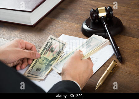Hohe Betrachtungswinkel von korrupten Richter zählen Geld am Schreibtisch im Gerichtssaal Stockfoto