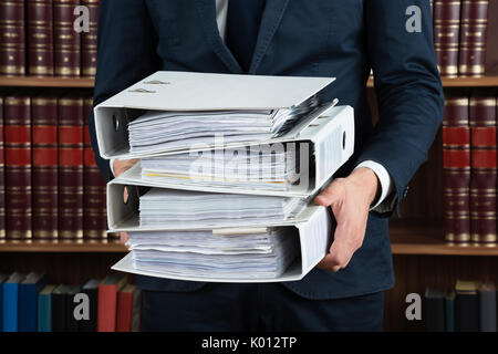Mittelteil der männlichen Rechtsanwalt die Stapel von Ringbüchern im Gerichtssaal Stockfoto