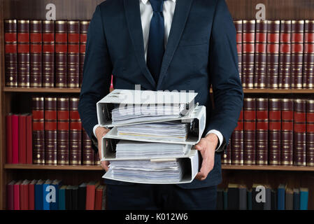 Mittelteil der männlichen Rechtsanwalt die Stapel von Ringbüchern im Gerichtssaal Stockfoto