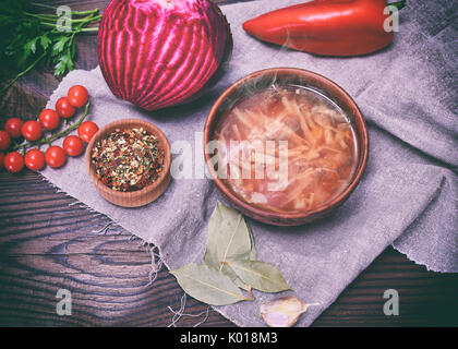 Traditionelle ukrainische Borsch in einer Runde braune Platte in der Mitte mit Gemüse und Zutaten auf einem Holztisch, Ansicht von oben Stockfoto