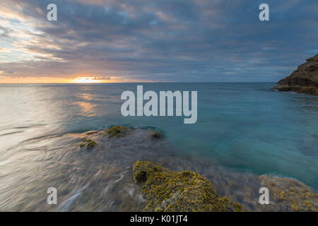 Das Licht des Sonnenuntergangs spiegeln sich in das blaue Meer Hawksbill Bay Karibik Antigua und Barbuda Leeward Islands West Indies Stockfoto
