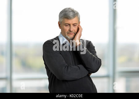 Nachdenklich, traurig reifer Mann. Ältere Menschen stehen auf unscharfen Hintergrund aufgebracht. Verloren in Gedanken. Stockfoto