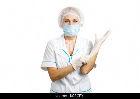 Weibliche Chirurgen setzen auf Handschuhe. Ärztin setzen auf weiße sterile OP-Handschuhe, weisser Hintergrund. Stockfoto