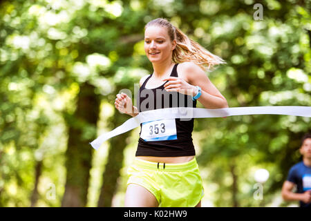 Junge Frau des Rennens Überqueren der Ziellinie. Stockfoto